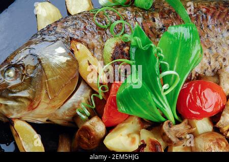 Gebackener Fisch mit Gemüse, Pilzen, Zitrone und Damson. Stockfoto