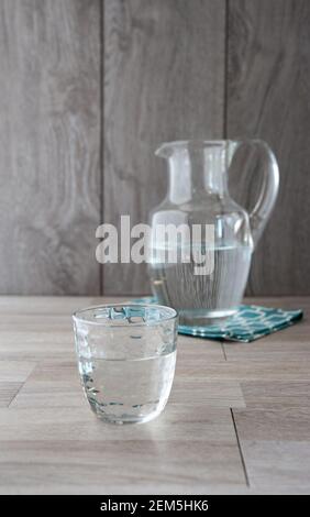 Glas voller Wasser, Wasserkrug im Hintergrund Stockfoto