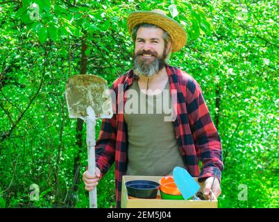 Professioneller Gärtner. Glücklicher bärtiger Mann im Garten. Öko-Farm. Männlich mit Gartengeräten. Stockfoto