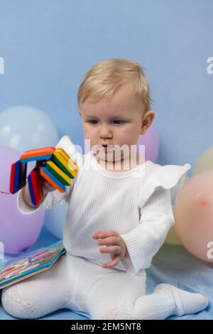 Ein kleines Mädchen in weißen Kleidern spielt begeistert mit einem Bunte Puzzle auf dem Spielplatz Stockfoto