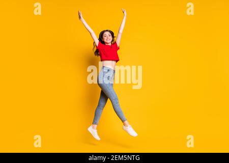 Foto in voller Größe von zufriedenen Mädchen springen Rest heben die Hände Tragen Sie Sneakers isoliert über helle Farbe Hintergrund Stockfoto