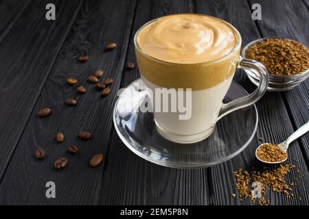 Dalgona Kaffee in der Glastasse auf dem schwarzen Holzhintergrund. Nahaufnahme. Stockfoto
