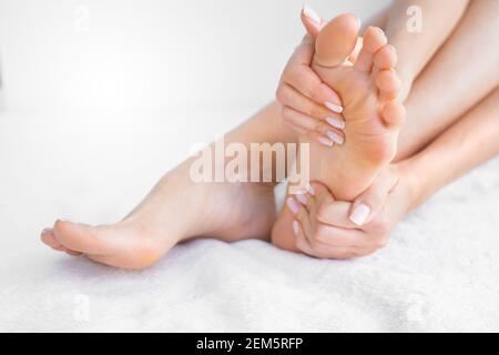 Frau auf weißem Hintergrund massiert ihren schmerzhaften Fuß Schmerzen lindern.Füße Schmerzen Stockfoto