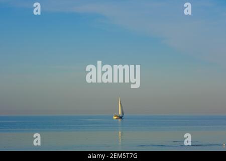 Ein weißes Segelschiff schwimmt auf dem Meer und der Wasser ist sehr ruhig Stockfoto