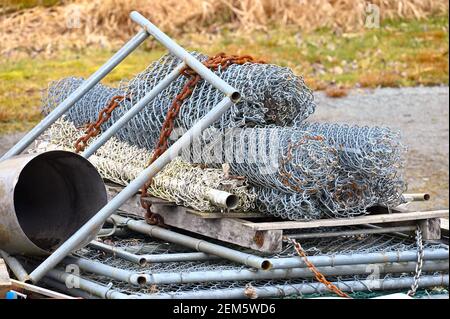Ein Stapel aufgerollter, weggeworfener Kettengliederzäune mit einer verrosteten Kette. Stockfoto