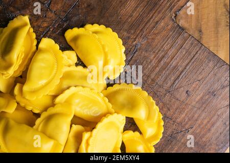 Kleine Ravioli mit gewellten Kanten, Käse oder Fleisch in Brühe zu kochen, ein traditionelles Gericht für Feiern in italien, Emilia Romagna Region. Frische hausgemachte Pasta mit Füllung auf einem Holztisch. Speicherplatz kopieren Stockfoto