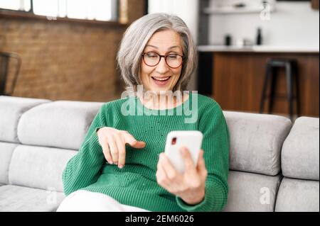 Happy Beautiful Senior Woman verwendet ein Smartphone für Videoanrufe zu Familie, Freunden oder Dating online. Ältere Dame hält das Telefon und mit App für Video-Kommunikation, Online-Meeting Stockfoto