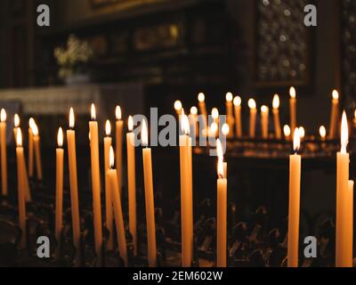 Brennende gelbe Kerzen mit der Abteilung des Feldes auf der dunklen Kirche Hintergrund Stockfoto