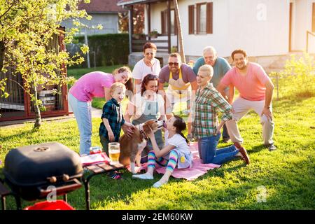 Die Familie bereitete sich darauf vor, fotografiert zu werden, als das junge süße Mädchen von einem Hund geküsst wurde, der an einem sonnigen Tag ihre Aufmerksamkeit wegnahm. Stockfoto