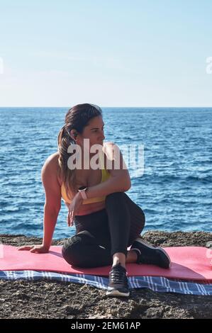 Lateinische Frau, mittleren Alters, ausruhen, Kraft zurückgewinnen, essen, Trinkwasser, nach einer Trainingseinheit, tragen orange Top, Kalorien zu verbrennen, fit zu bleiben, Stockfoto