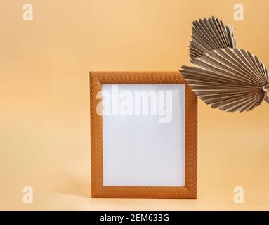 Bild Holzrahmen und trockenen Zucker Palmblätter auf dem beige neutralen Hintergrund Nahaufnahme. Mockup-Vorlage mit weißem Rohling für die Anzeige Ihres Bildes o Stockfoto