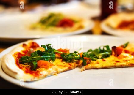 Unschärfe unfertige Stücke Pizza auf einem Teller in Pizza-Restaurant. Ein Stück Käse Pizza auf rustikalem Tisch. Konzept der Food-Fotografie. Nahaufnahme. Aus Stockfoto