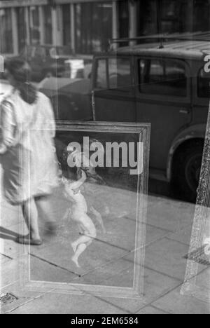 Großbritannien, West London, Notting Hill, 1973. Reflexionen in einem Schaufenster verkaufen Antiquitäten & Gemälde. Stockfoto