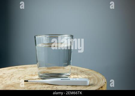 Wasserglas und Thermometer auf Holztisch Stockfoto