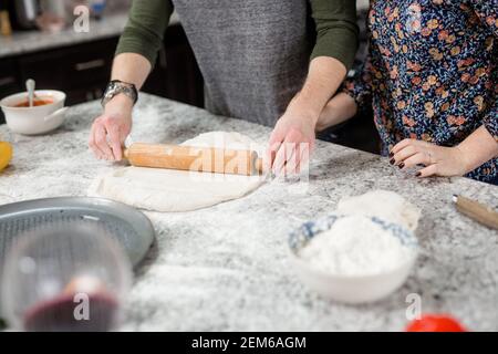 Paar Kochen in der Küche, Ausrollen Pizzateig mit Rolling Pin Stockfoto