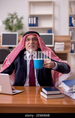 Gealterter arabischer Angestellter, der während der Pause Kaffee trinkt Stockfoto