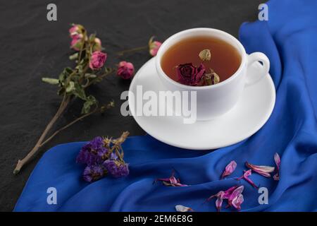 Getrocknete Rosen mit einer Tasse heißen Tee auf einem Schwarzer Hintergrund Stockfoto