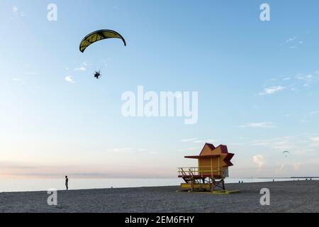 Ein motorbetriebener Gleitschirm fliegt über einen der legendären Rettungsschwimmer-Türme von South Beach, Miami, Florida Stockfoto