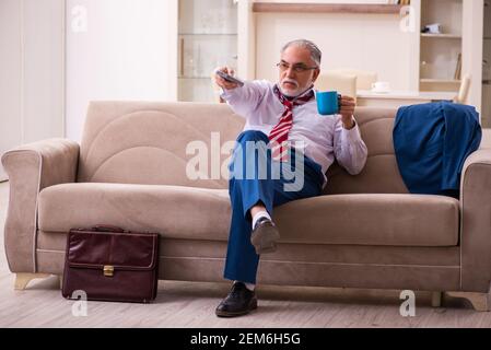 Leitender männlicher Chef-Angestellter, der zu Hause Fernsehen schaut Stockfoto