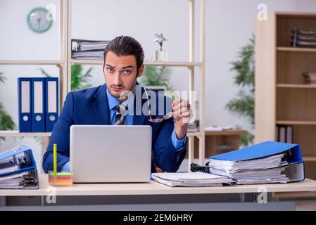 Junge männliche Mitarbeiter mit übermäßiger Arbeit unzufrieden Stockfoto