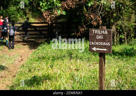 Ein Holzschild in Richtung Trilha das Cachoeiras (Wasserfall Wanderweg) Pfad in Serra do Mar Landgut Park, Cunha Kern. Stockfoto