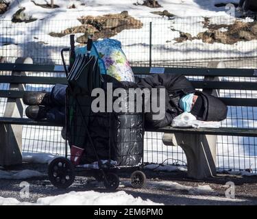 New York, New York, USA. Februar 2021, 24th. Ein Obdachloser ruht auf einer Bank im Central Park in New York City. Kredit: Debra L. Rothenberg/ZUMA Wire/Alamy Live Nachrichten Stockfoto