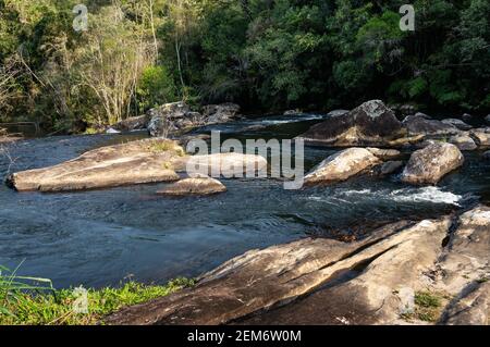 Paraibuna Fluss kristallklares Wasser fließt um Felsformationen in der Mitte des Flusses und dichten Sea Ridge (Serra do Mar) Dschungel. Stockfoto