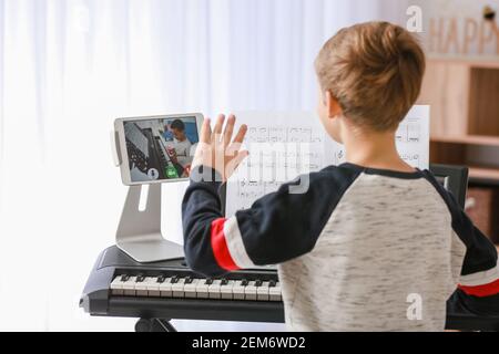 Kleiner Junge studiert Musik mit seinem Freund online zu Hause Stockfoto