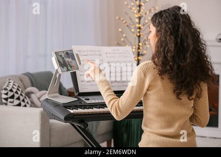 Junge Frau gibt Musikunterricht online zu Hause Stockfoto