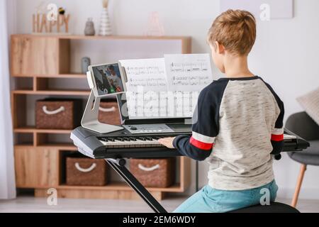 Kleiner Junge studiert Musik mit seinem Freund online zu Hause Stockfoto