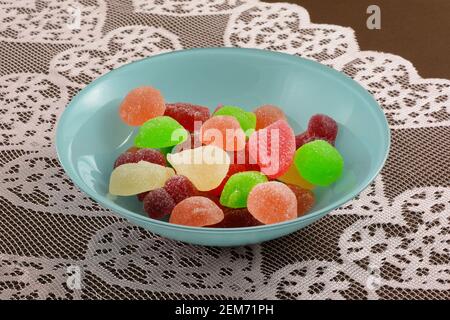 Sommerfrucht Birne, Aprikose, grüner Apfelpfirsich und Wassermelone Saft gefüllt Gummy Süßigkeiten Gelees in blauer Schale auf Spitze Tischläufer auf Tischdecke Stockfoto