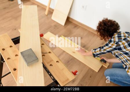 Nahaufnahme eines Holzsandpapiers auf einer Werkbank mit einer Frau im Hintergrund. Innenaufnahme. Tageslicht. Stockfoto