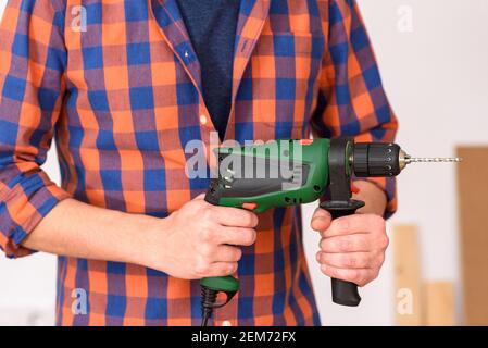 DIY Enthusiast Mann hält eine Bohrmaschine. Weißer Hintergrund. Unifarbenes Hemd. Stockfoto