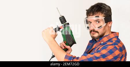 DIY Enthusiast Mann hält eine Bohrmaschine. Weißer Hintergrund. Unifarbenes Hemd. Stockfoto