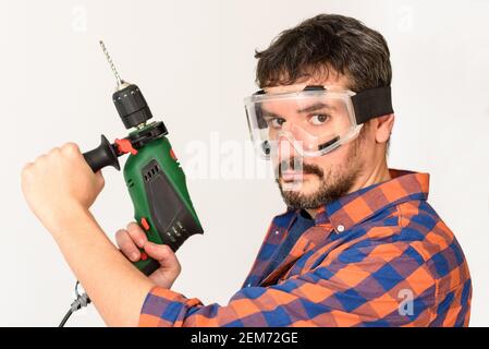 DIY Enthusiast Mann hält eine Bohrmaschine. Weißer Hintergrund. Unifarbenes Hemd. Stockfoto