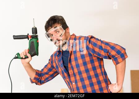 DIY Enthusiast Mann hält eine Bohrmaschine. Weißer Hintergrund. Unifarbenes Hemd. Stockfoto