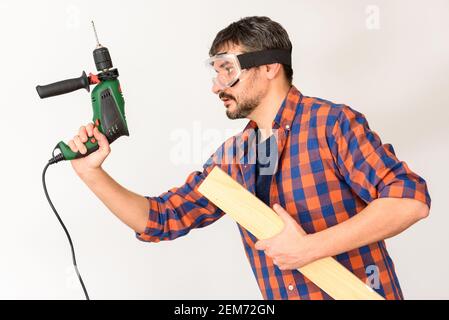 DIY Enthusiast Mann hält eine Bohrmaschine. Weißer Hintergrund. Unifarbenes Hemd. Stockfoto