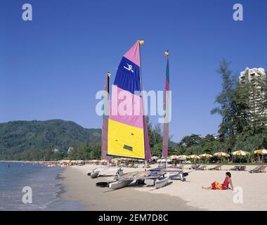 Asien, Thailand, Phuket Island, bunte Outrigger Kanus und Touristen Sonnenbaden am Patong Beach Stockfoto