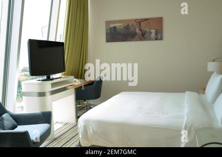 Modernes, gemütliches Schlafzimmer im Dachgeschoss mit Tageslicht durch das Fenster, Kingsize-Bett, Stühlen, fernseher und Tisch mit Lampe Stockfoto