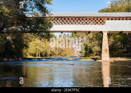 Cleveland, Alabama/USA - Okt 17, 2020: Zwei Kajakfahrer kommen die Locust Fork des Black Warrior River hinunter zur historischen Swann Covered Bridge. Stockfoto