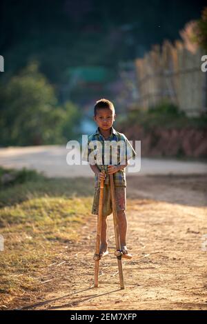 Chiang Mai / Thailand - Jan 16 2016 : EIN Junge, der Gong Keng spielt, ist ein traditionelles thailändisches Spielzeug, das Bambus verwendet, um zwei Beine höher zu gehen. Es gibt ein d Stockfoto