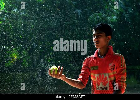 Cumilla, Bangladesch - 24. November 2017: Der Junge spritzt mit einem Cricket-Ball Wasser Stockfoto