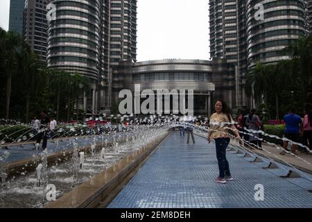 KUALA LUMPUR, MALASIA – 26. JANUAR 2020 Menschen spielen in den Wasserfontänen am Fuße der Petronas Twin Towers Stockfoto