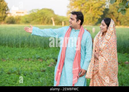 Glücklich junge indische ländliche Bauern Paar in landwirtschaftlichen Feld Blick auf einander lachen. Copy Raum, um Text zu schreiben. Mann trägt Kurta und Frau wea Stockfoto