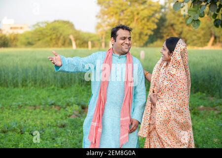 Glückliche junge indische ländlichen Bauern Paar in landwirtschaftlichen Feld Blick auf einander lachen. Stockfoto