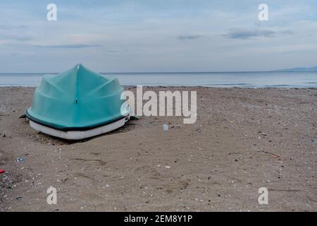 Türkisfarbenes Fischerboot am Strand mit Meer und Himmel Hintergrund. Stockfoto