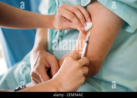 Nahaufnahme der Hände einer jungen Ärztin, die Impfungen gibt Injektion an jungen männlichen Patienten auf den Armen zur Prävention gegen Covid-19 Pandemie Stockfoto