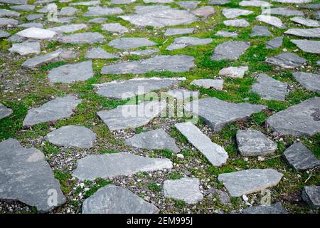 Alte und Retro-Stil Weg. Es besteht aus Steinen und grünem Gras wachsen Lücken zwischen Steinen. Stockfoto