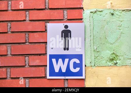 Zeichen der Toilette (Wasserschrank) hängen auf roten Ziegeln. WC-Schild hängt auf der man-Toilette. Stockfoto