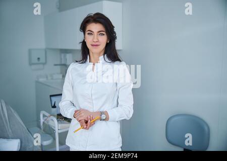 Beschaulicher dunkelhaariger Arzt in Uniform, der nach vorne schaut Stockfoto
